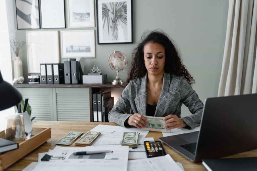 professional woman counting cash at office desk with calculator and documents illustrating final paycheck laws by state