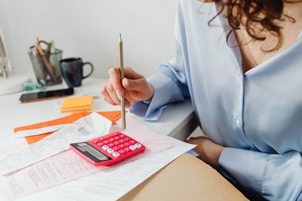 woman calculating invoice due dates with a calculator to check net 30 business days or calendar days